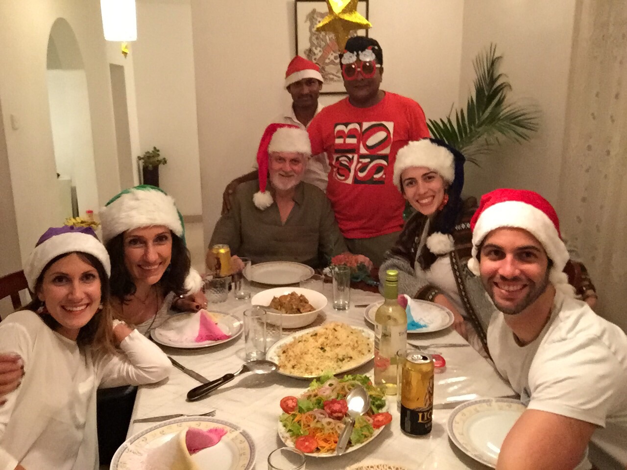Guests and hosts smiling around the dining table during a festive meal